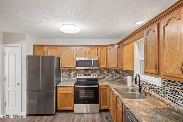 kitchen with a sink, dark wood-style floors, backsplash, and stainless steel appliances