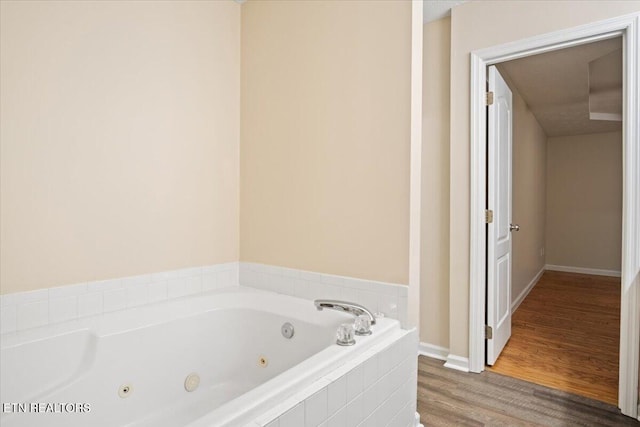 bathroom featuring a jetted tub, baseboards, and wood finished floors