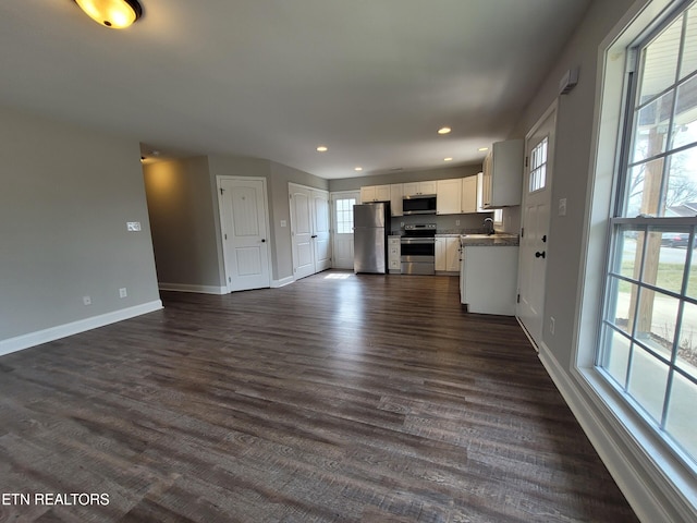 kitchen with a sink, stainless steel appliances, dark wood-type flooring, and open floor plan