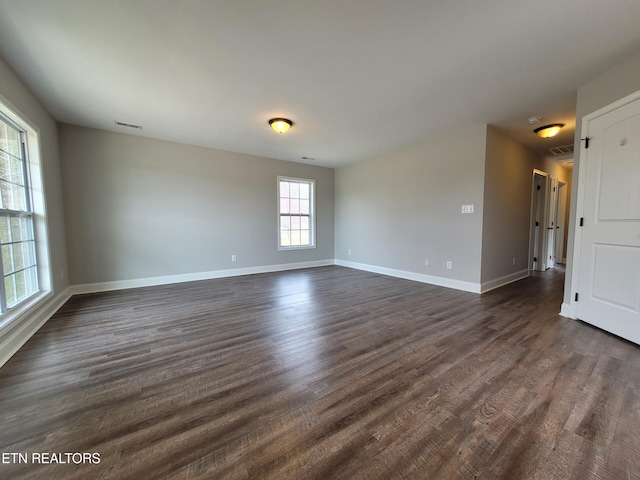 spare room with visible vents, baseboards, and dark wood-style flooring