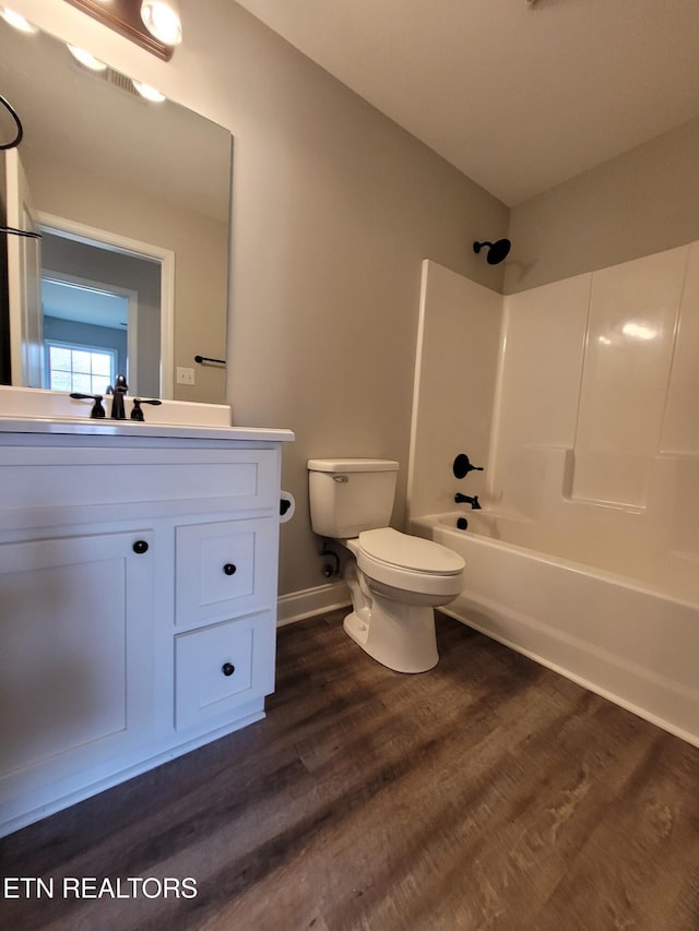 full bath with vanity, wood finished floors, baseboards, shower / bath combination, and toilet