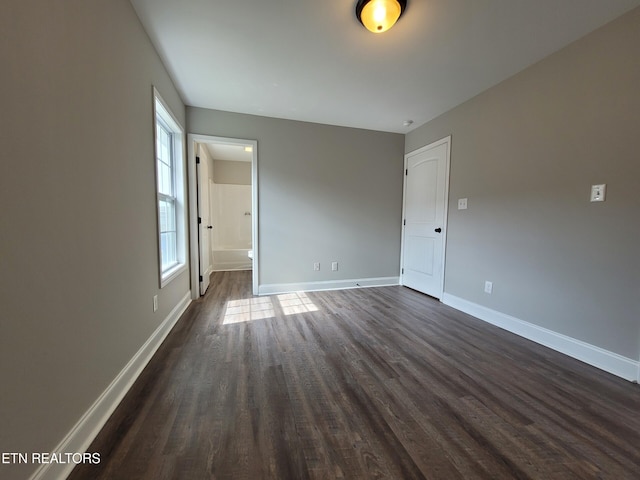 unfurnished room featuring baseboards and dark wood-style flooring