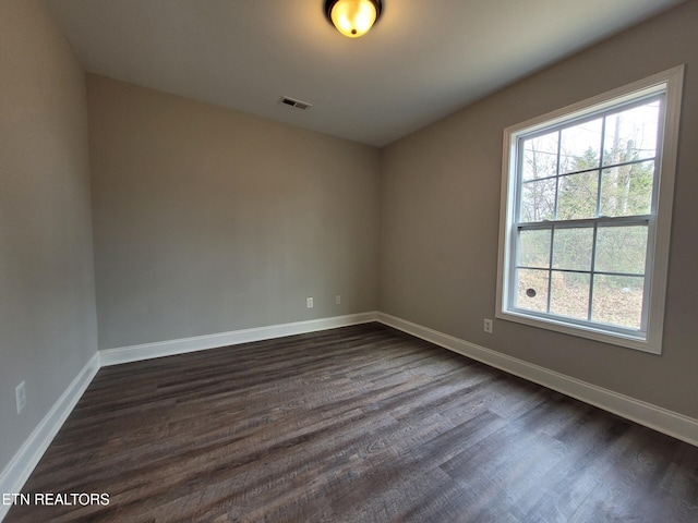 spare room with visible vents, dark wood-type flooring, and baseboards