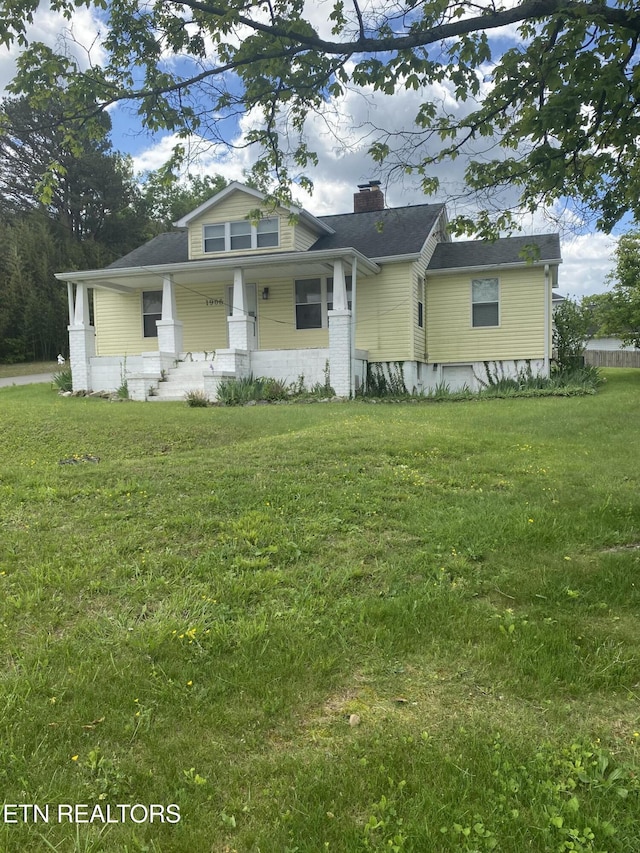 bungalow-style house featuring covered porch, a chimney, and a front lawn