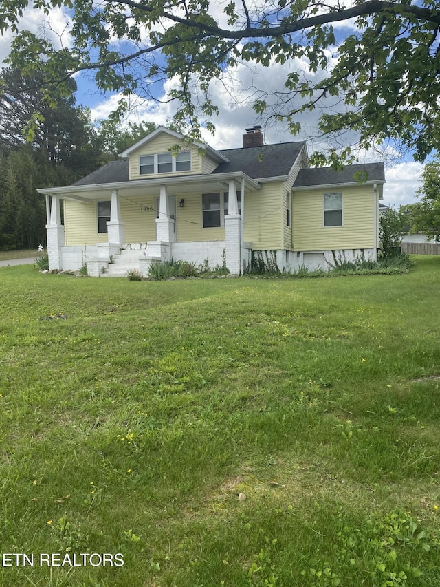 bungalow featuring a chimney, a porch, and a front lawn