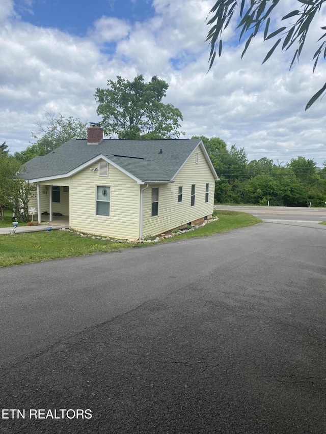 view of side of property featuring roof with shingles and a chimney