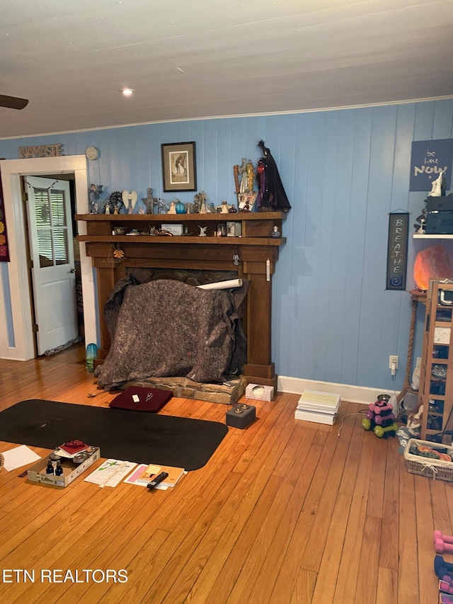 interior space featuring a fireplace with raised hearth, baseboards, and hardwood / wood-style floors