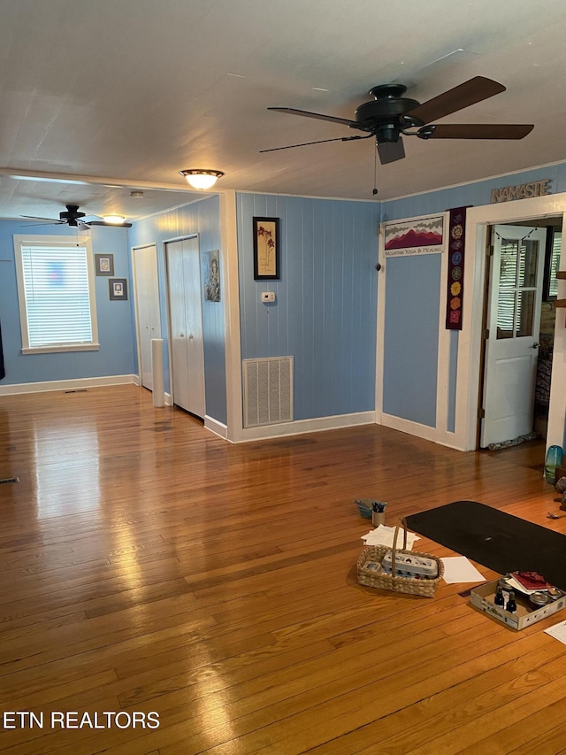 unfurnished living room featuring visible vents, baseboards, ceiling fan, and wood finished floors