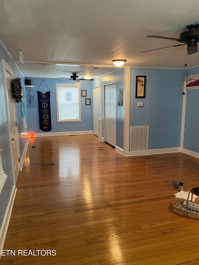 unfurnished living room featuring visible vents, baseboards, ceiling fan, and wood finished floors