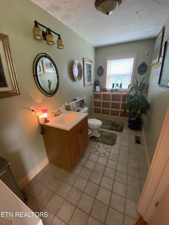 bathroom featuring toilet, a textured ceiling, tile patterned flooring, baseboards, and vanity