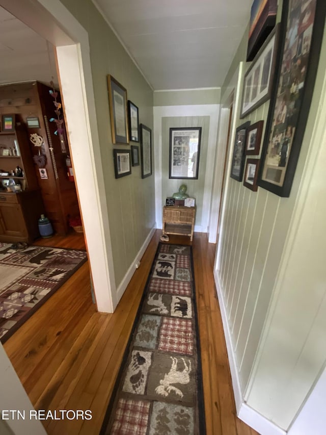 corridor featuring baseboards and hardwood / wood-style flooring