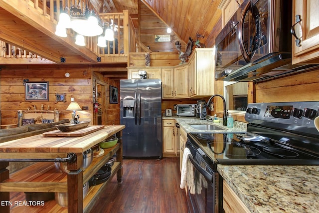 kitchen featuring wood walls, vaulted ceiling, appliances with stainless steel finishes, a notable chandelier, and a sink