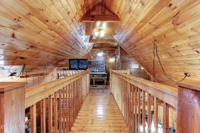 hall with hardwood / wood-style floors, an upstairs landing, wood walls, and wooden ceiling