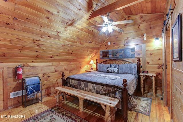 bedroom with hardwood / wood-style floors, lofted ceiling with beams, a barn door, wood walls, and wooden ceiling