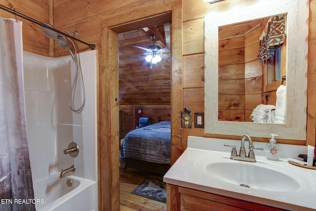 bathroom with vanity, wooden walls, shower / bath combo with shower curtain, and ceiling fan