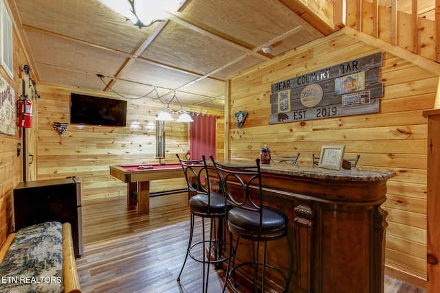 bar featuring pool table, a dry bar, wood finished floors, and wood walls