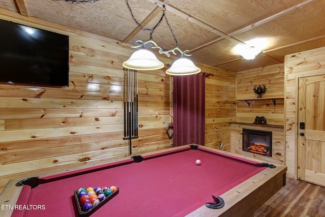 game room featuring wood walls, a warm lit fireplace, billiards, and wood finished floors