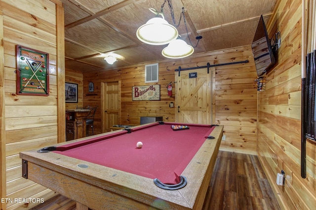 rec room featuring a barn door, wooden walls, visible vents, and wood finished floors