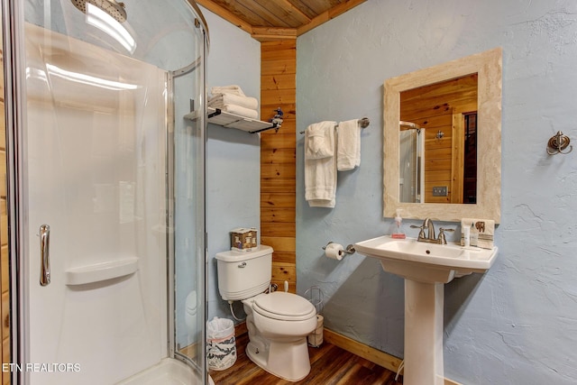 full bathroom featuring a shower stall, toilet, wood finished floors, and a textured wall