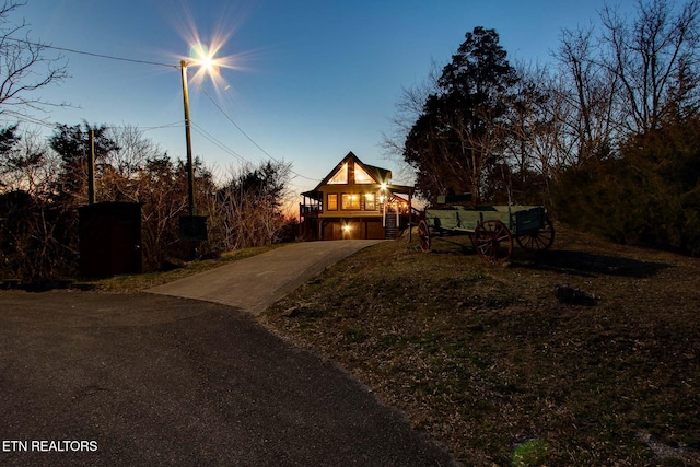 view of front of property with concrete driveway, stairs, covered porch, a lawn, and a garage