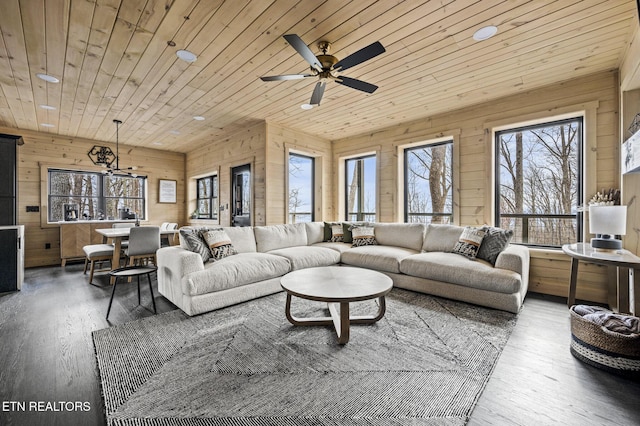 living area featuring wood finished floors, wooden ceiling, a ceiling fan, and wood walls