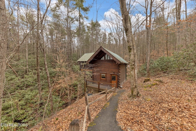 view of side of property with aphalt driveway, log siding, and a forest view