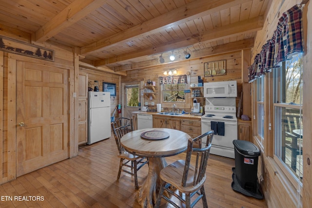 dining area with light wood-style floors, beam ceiling, wooden walls, and wood ceiling