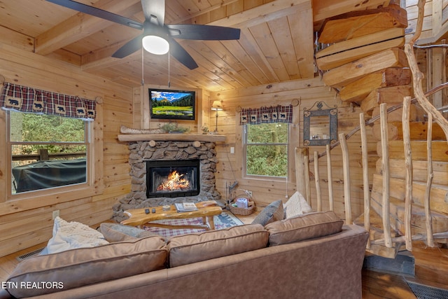 living area with visible vents, wood walls, wood ceiling, a stone fireplace, and wood finished floors