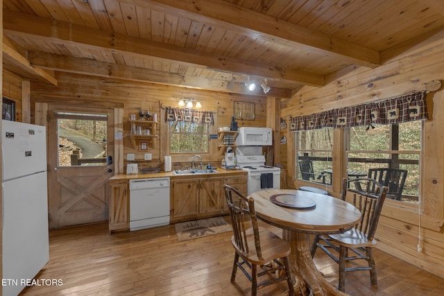 kitchen with a sink, light wood-type flooring, white appliances, and wooden walls