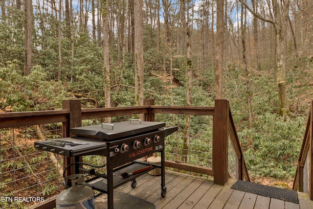 wooden deck featuring area for grilling and a wooded view