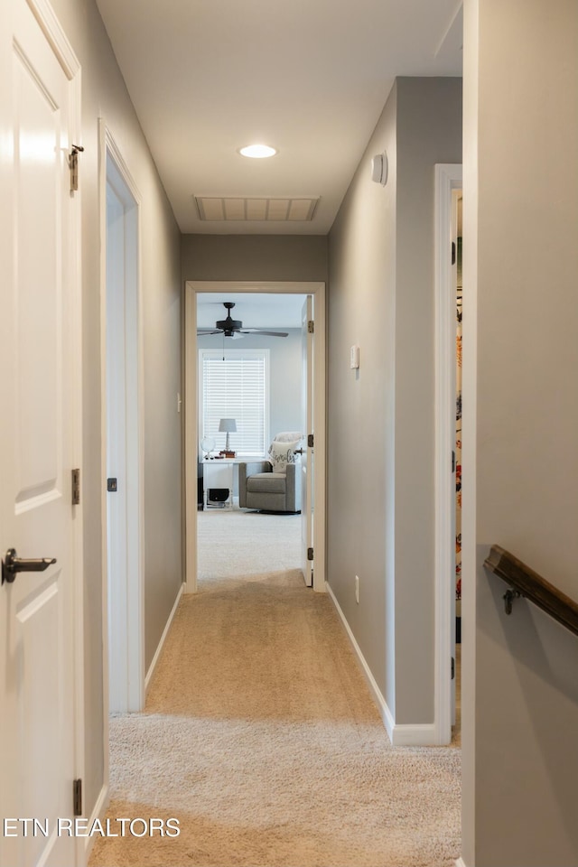 hallway with visible vents, baseboards, and carpet