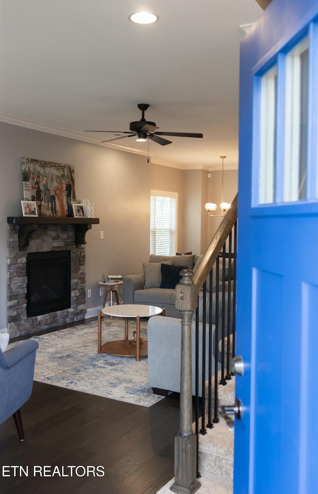 living area with crown molding, ceiling fan, a stone fireplace, recessed lighting, and wood finished floors