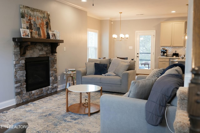 living room featuring a notable chandelier, wood finished floors, a fireplace, crown molding, and baseboards