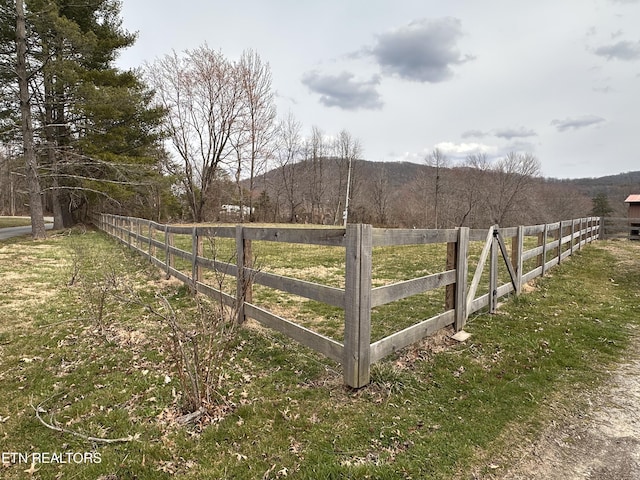 view of yard with a view of trees, a rural view, and fence