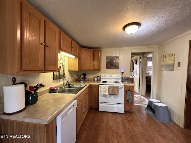 kitchen featuring white appliances, brown cabinetry, dark wood-style flooring, a sink, and light countertops