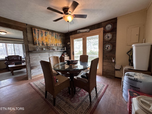 dining area featuring hardwood / wood-style floors, wooden walls, and a healthy amount of sunlight