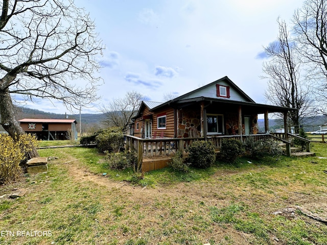 view of side of home with a yard, stone siding, and a porch