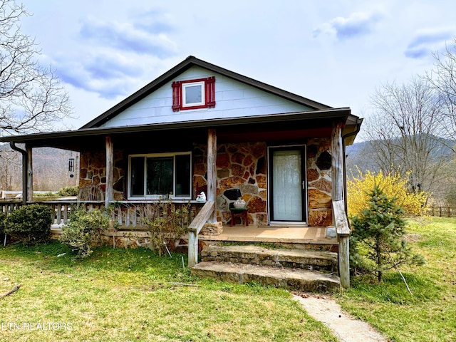 view of front of house with a porch, stone siding, and a front lawn