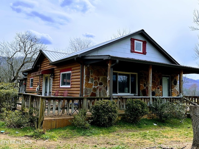 view of front of property featuring metal roof, stone siding, and covered porch