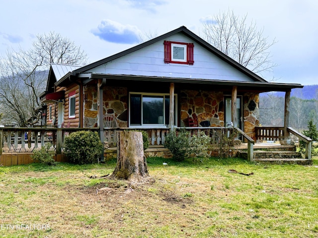 view of front facade with stone siding, a porch, metal roof, and a front yard