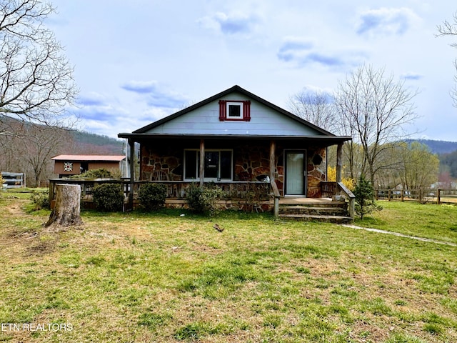 view of front of home featuring a front yard, covered porch, and stone siding