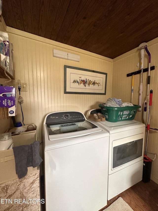 clothes washing area with washing machine and clothes dryer, laundry area, wood ceiling, and wood finished floors