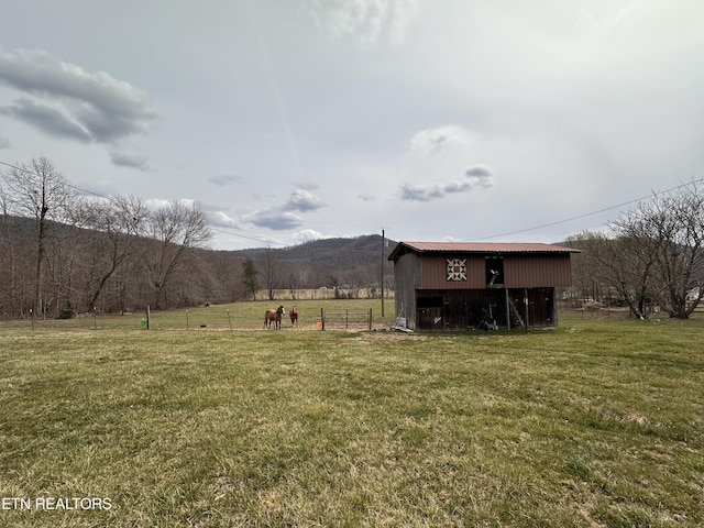 view of yard with a mountain view, a rural view, an outdoor structure, and fence