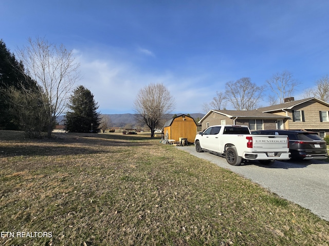 view of yard featuring a storage unit, an outbuilding, and driveway