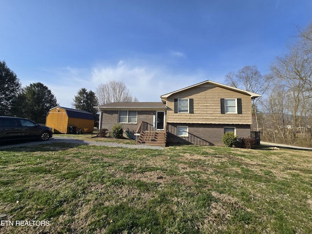 split level home featuring brick siding, a shed, an outdoor structure, and a front lawn