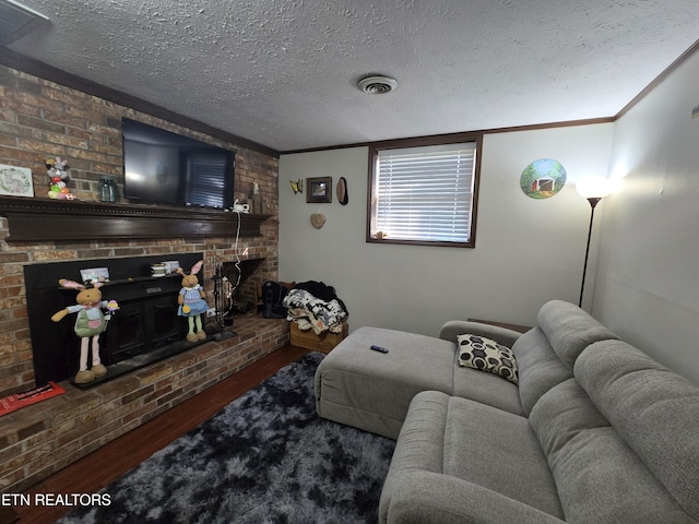 living room featuring ornamental molding, a fireplace, a textured ceiling, and wood finished floors