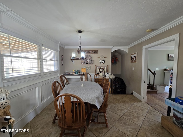 dining area featuring stairs, ornamental molding, light tile patterned floors, arched walkways, and a textured ceiling