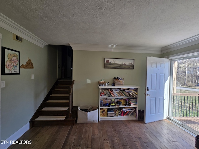 stairs with hardwood / wood-style floors, crown molding, visible vents, and a textured ceiling