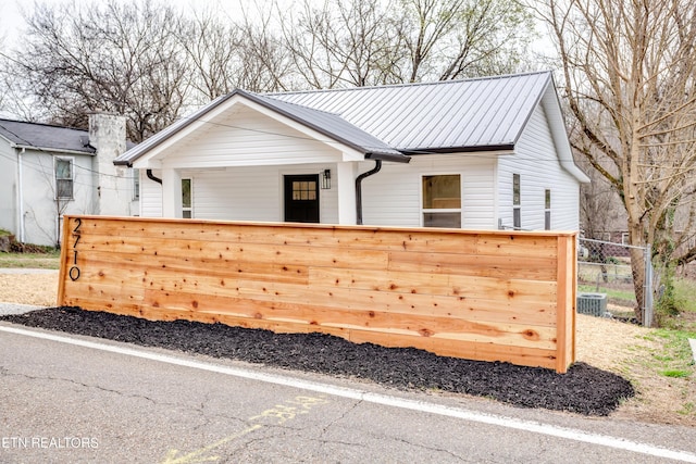 modern farmhouse style home featuring central air condition unit, metal roof, and fence