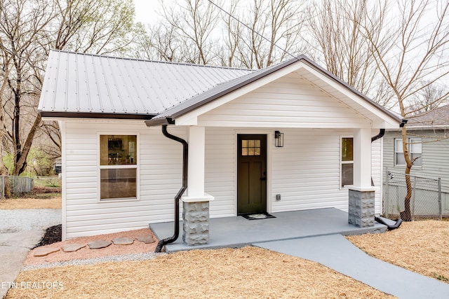 view of front of house featuring a porch, fence, and metal roof